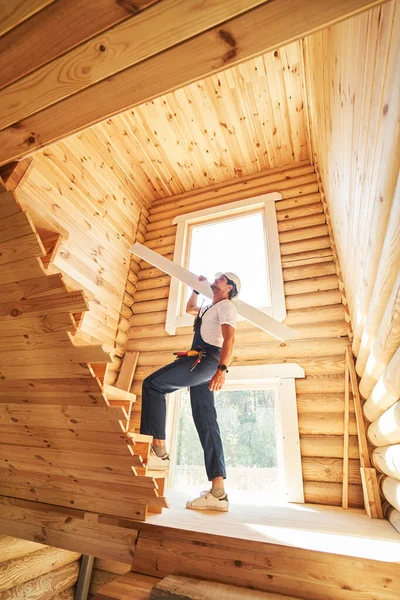 Byggherre gör ett steg på trappor med bräda på axeln — Stockfoto