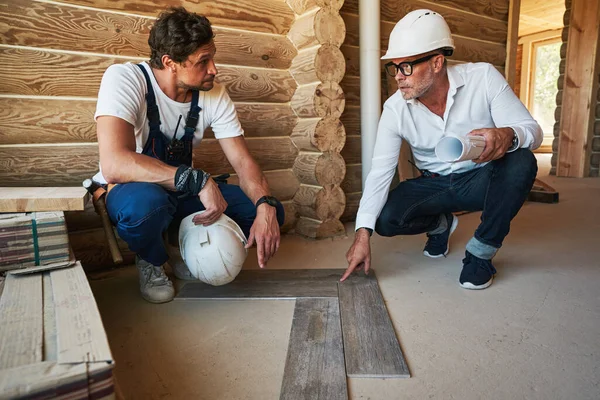 Byggnadsingenjör som talar om för byggmästaren hur man lägger parquetry — Stockfoto