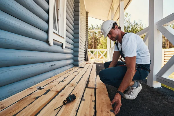 Domácí stavitel pokládá podlahy na verandu domu — Stock fotografie