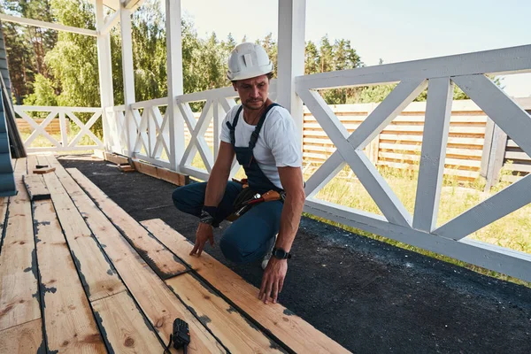 Byggherre huk och trycka på golvbrädan för att veranda marken — Stockfoto