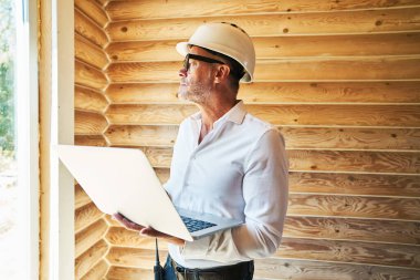 İnşaat mühendisi, bina içinde dizüstü bilgisayarla çalışıyor.