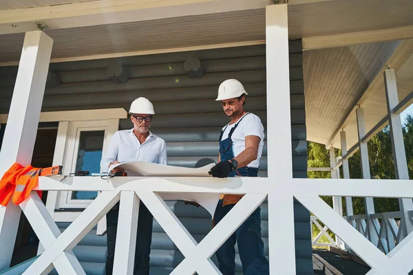 Paret byggingenjörer läser ritningar på verandan — Stockfoto