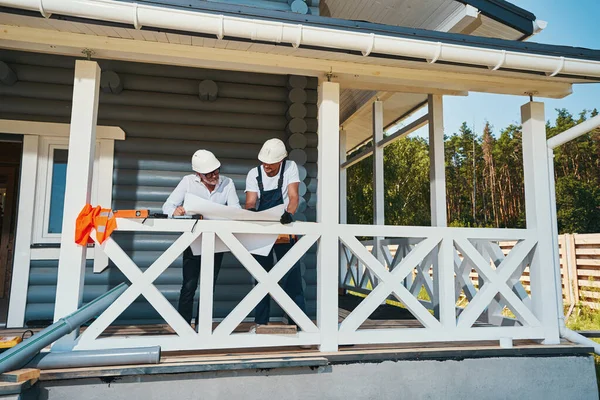 Dva muži na verandě kontrolují technický dokument — Stock fotografie