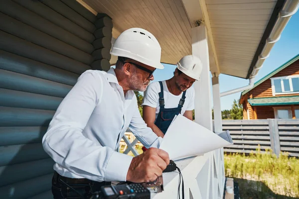 Geconcentreerd leesdocument voor oudere ingenieur en bouwer — Stockfoto