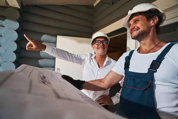 Lachende bouwers schatten de hoeveelheid werk met lay-out — Stockfoto