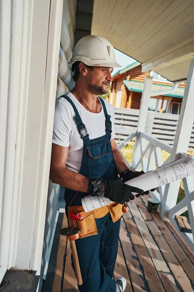 Muž stavitel s pásem s nářadím drží role papíru — Stock fotografie
