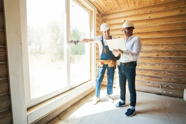 Arbetare och byggnadsingenjör studerar information från bärbar dator — Stockfoto