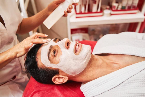 Esteticista poner mascarilla crema facial en la cara del hombre — Foto de Stock