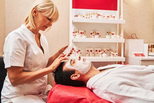 Kosmetický terapeut nanáší krém na obličej na mužského zákazníka — Stock fotografie