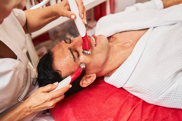 美容師圧延電気刺激マッサージ師上の男の顔 — ストック写真