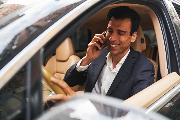 Empresario riendo durante conversación telefónica dentro de un coche — Foto de Stock