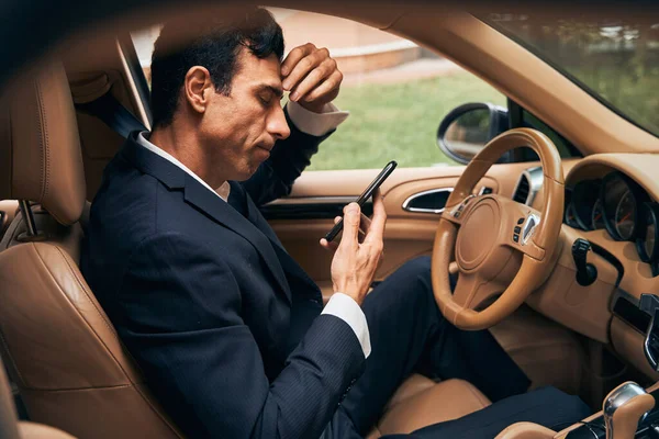 Empresario en coche estudiando su reflexión en la pantalla del smartphone — Foto de Stock