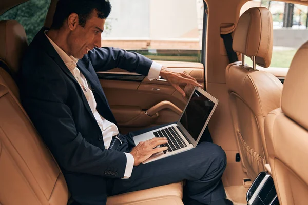 Специалист по бизнесу с ноутбуком на автомобильном пассажирском сидении — стоковое фото