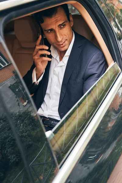 Empresario mirando al aire libre desde el coche mientras habla por teléfono — Foto de Stock