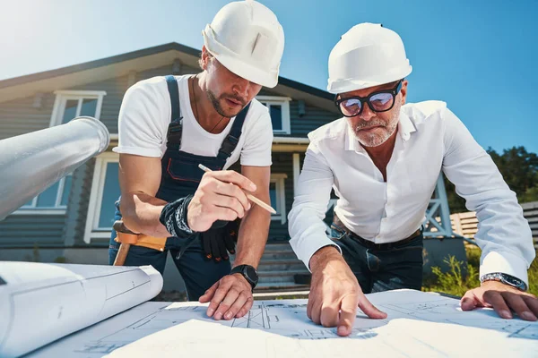 Twee ingenieurs bestuderen tekeningen van huizen. — Stockfoto