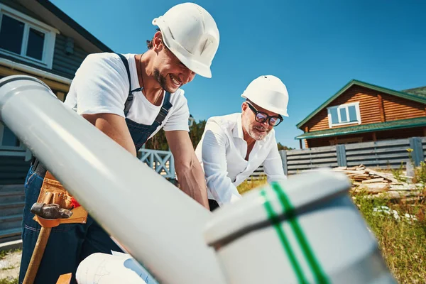 Byggarbetare i hjälmar lutande över bord — Stockfoto