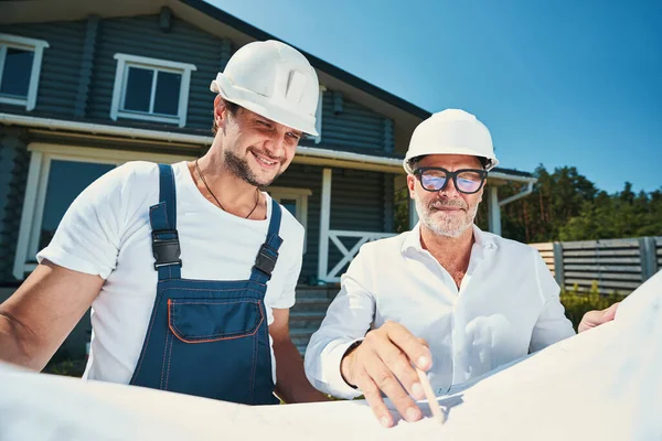 Erfarna konstruktörer som pekar läge på husets layout — Stockfoto