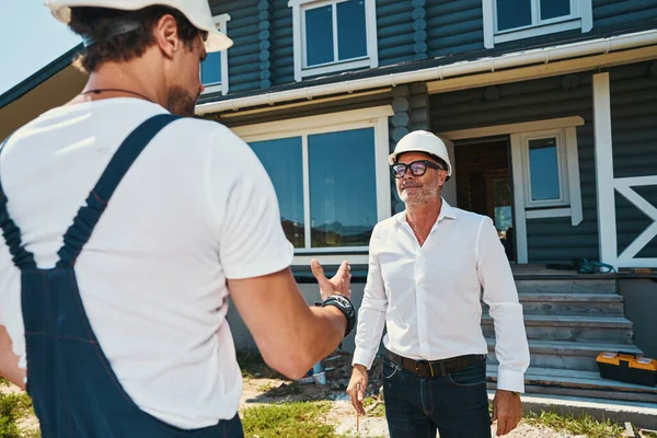 Manlig byggmästare ger förklaring till sin äldre medarbetare — Stockfoto