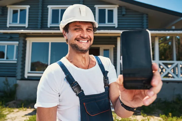 Trotse huisbouwer toont telefoonhoes in de hand — Stockfoto