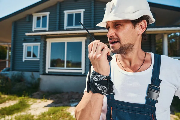 Engenheiro civil se comunicando com alguém através de walkie talkie — Fotografia de Stock