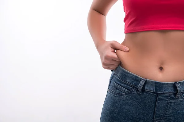 Primer plano de las mujeres cintura pellizco exceso de grasa en blanco backgr — Foto de Stock