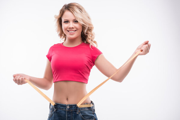 Тонкая талия молодой женщины в больших джинсах с измерительной лентой showi
