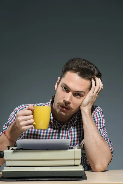 Författare dricker kaffe på skrivmaskin — Stockfoto