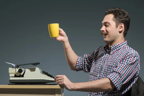 Författare dricker kaffe på skrivmaskin — Stockfoto