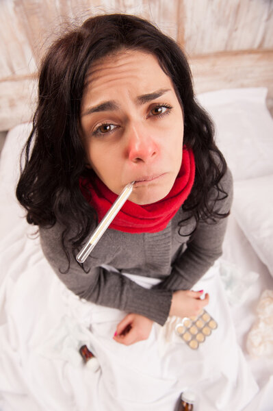 Frustrated woman lying in bed with pills