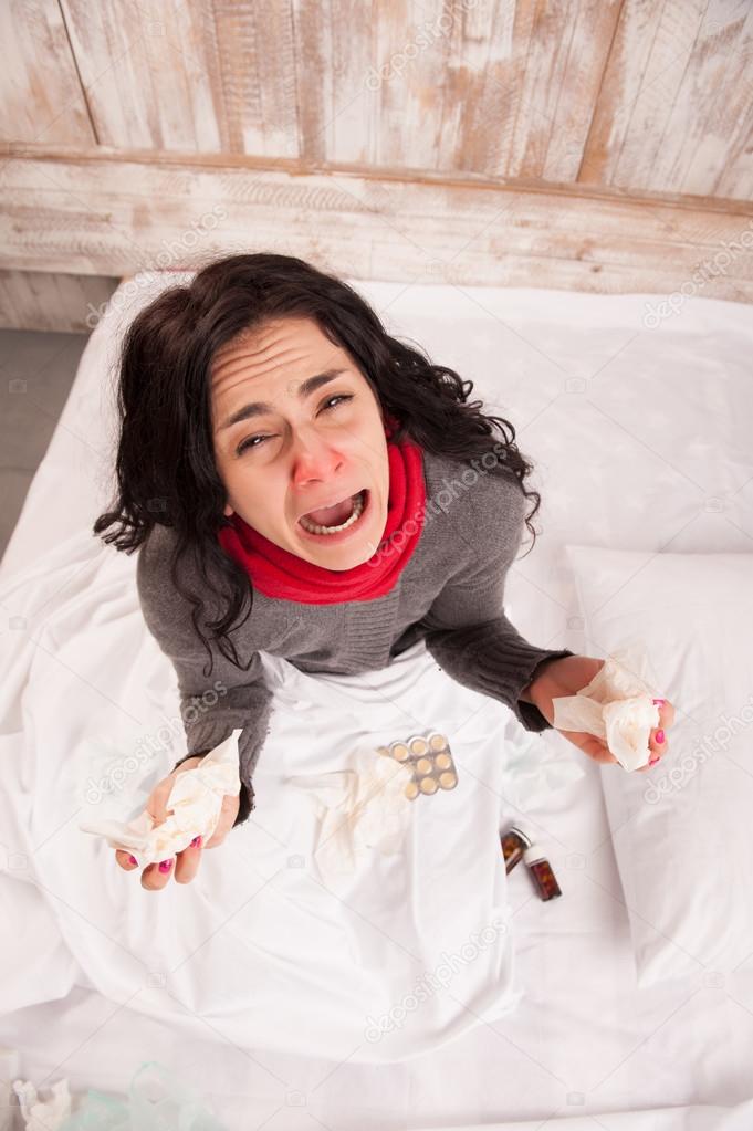 Frustrated woman lying in bed with pills