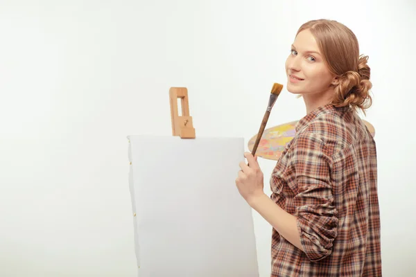 Joven artista hermosa posando con un caballete de dibujo y paleta — Foto de Stock