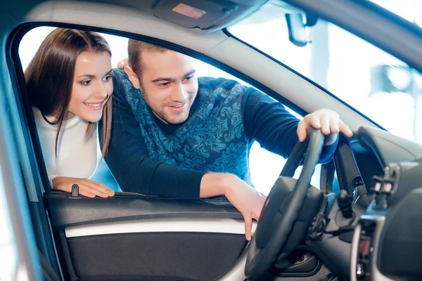 Interested couple examines a new car in showroom Royalty Free Stock Photos