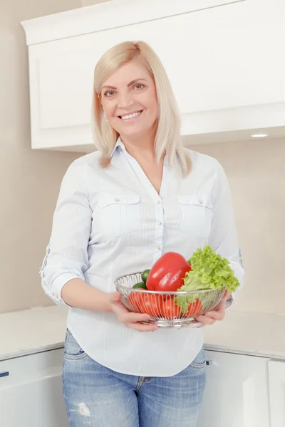 Mulher segura um prato com legumes — Fotografia de Stock