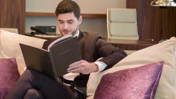 Joven guapo hombre leyendo una revista — Vídeo de stock