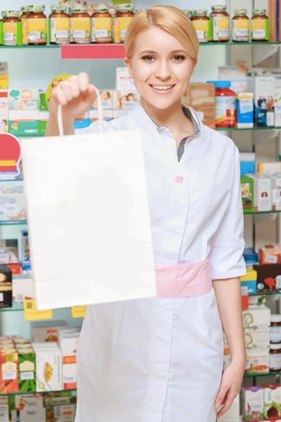 O farmacêutico estende o saco de papel — Fotografia de Stock