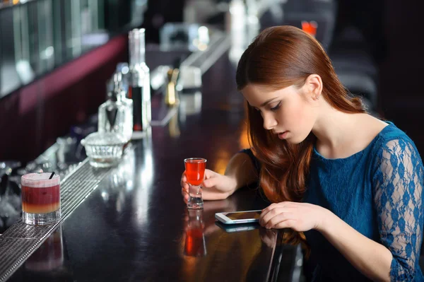 Νεαρή γυναίκα χρησιμοποιεί το τηλέφωνό της στο μπαρ — Φωτογραφία Αρχείου