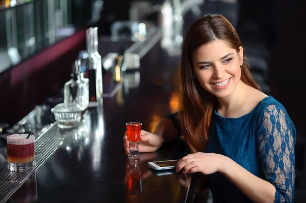 Young woman uses her phone in the bar — Stock Photo, Image