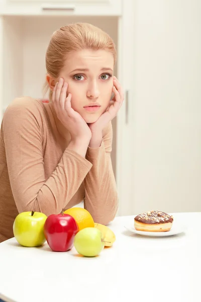 Mujer eligiendo entre fruta y donut — Foto de Stock