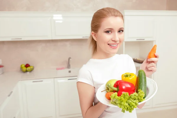 Woman holds plate with vegetables — Stock Photo, Image