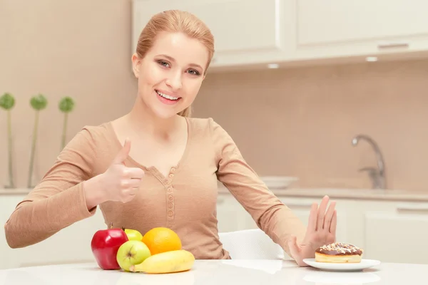 Sonriente dama se sienta entre la fruta y el postre —  Fotos de Stock