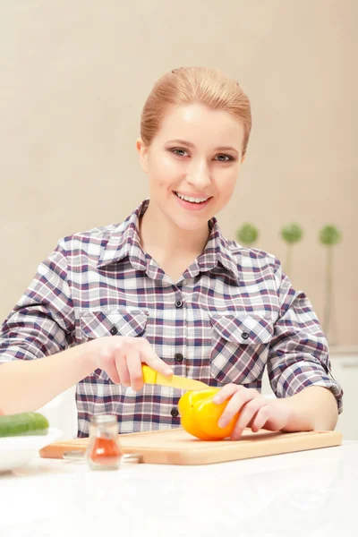 Young woman slices yellow pepper — Stock Photo, Image