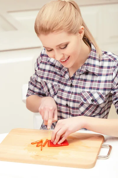 Pretty woman slices red pepper — Stock Photo, Image