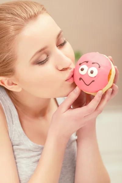 Jovem senhora beija um donut rosa — Fotografia de Stock