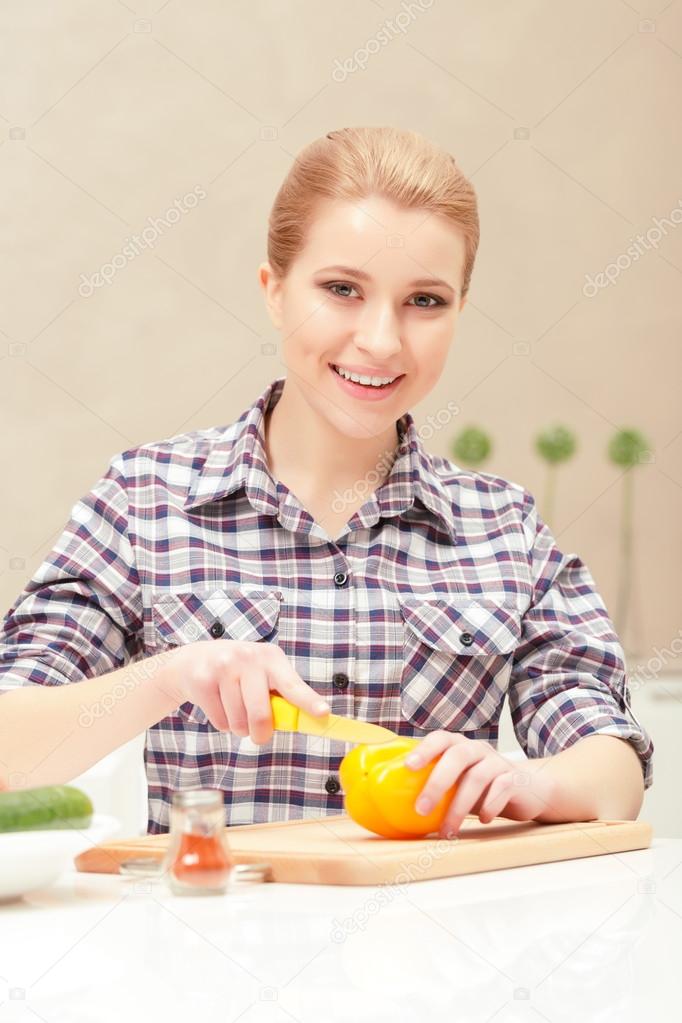 Young woman slices yellow pepper