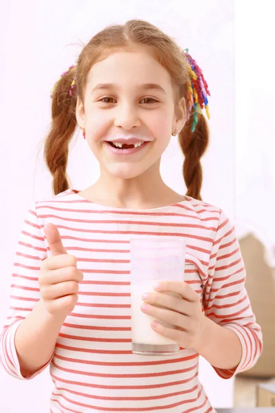 Маленькая девочка позирует со стаканом молока — стоковое фото