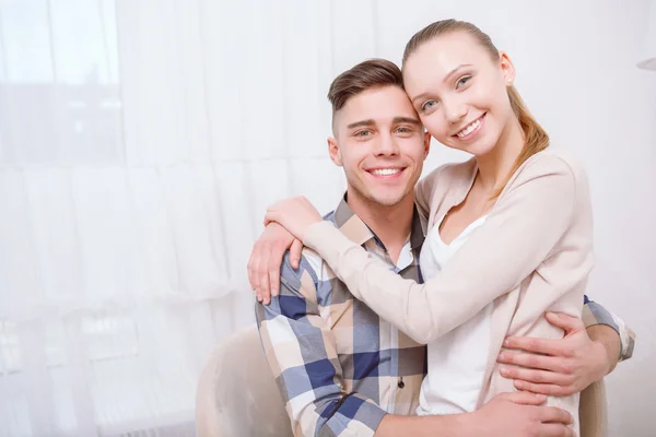 Jovem casal encantador sentado e abraçando — Fotografia de Stock