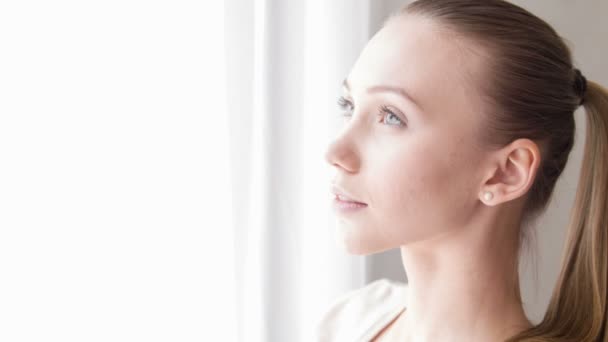 Mujer joven mirando a la ventana — Vídeos de Stock