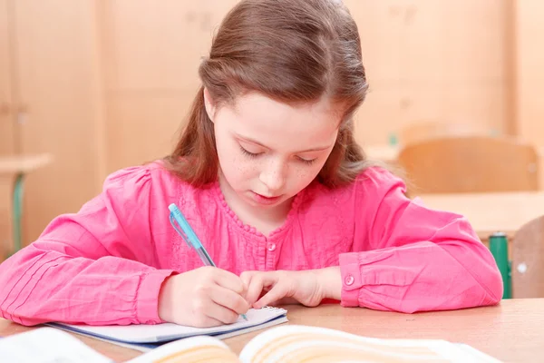 Pequena menina escrita durante as aulas — Fotografia de Stock