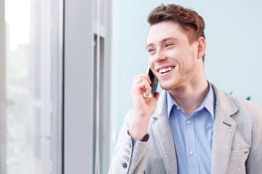 Genç gülümseyen adam cep telefonu konuşurken