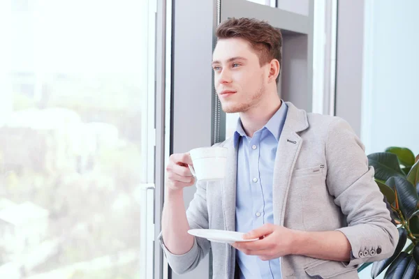 Jeune homme beau avec du café au bureau — Photo